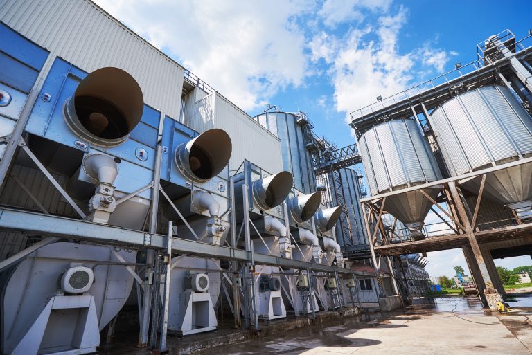 Agricultural Silos. Building Exterior. Storage and drying of grains, wheat, corn, soy, sunflower against the blue sky with white clouds.